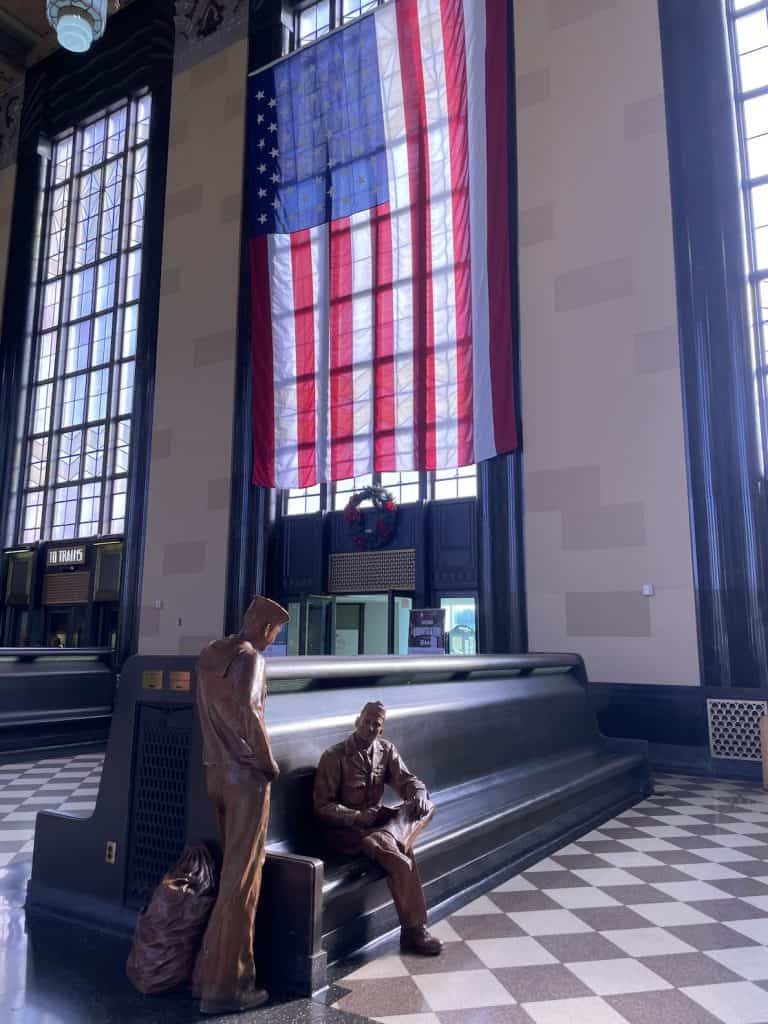 durham-museum-passenger-terminal-statues-sitting-in-historic-pues-with-huge-geometrical-windows-and-a-massive-american-flag