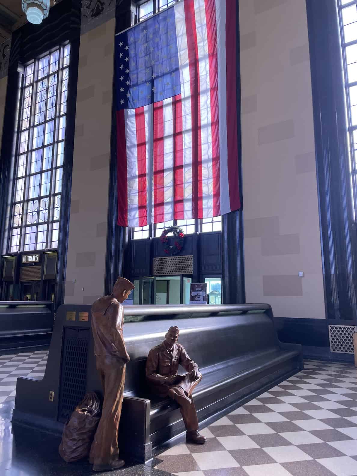 durham-museum-passenger-terminal-statues-sitting-in-historic-pues-with-huge-geometrical-windows-and-a-massive-american-flag