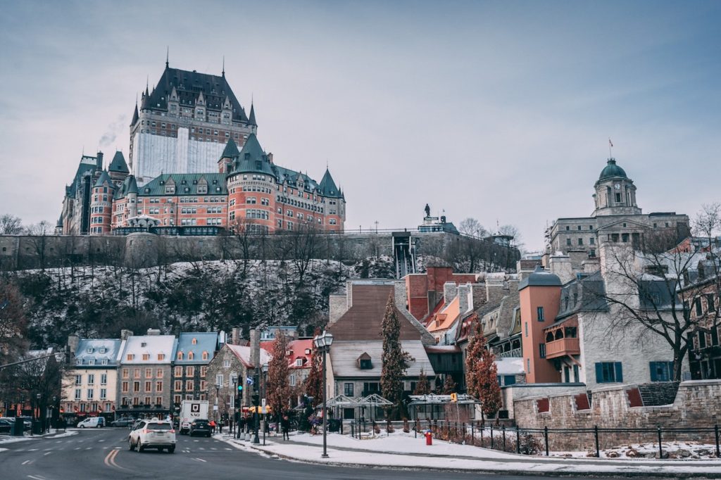 Huge hotel atop hill with smaller stone buildings below on cold winter day. Fairmont Le Chateau Frontenac, Quebec City, Canada
