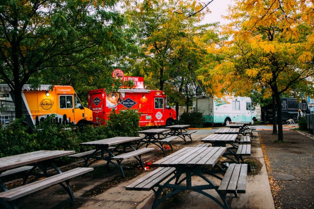 Food trucks lined up behind empty picnic benches on gloomy fall day.