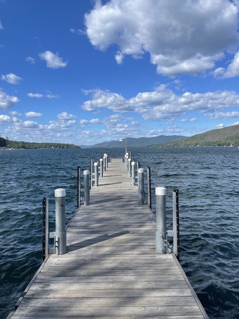 Dock extending out into huge lake with mountains in background on sunny day. Lake George, Upstate, New York - Upstate New York in fall