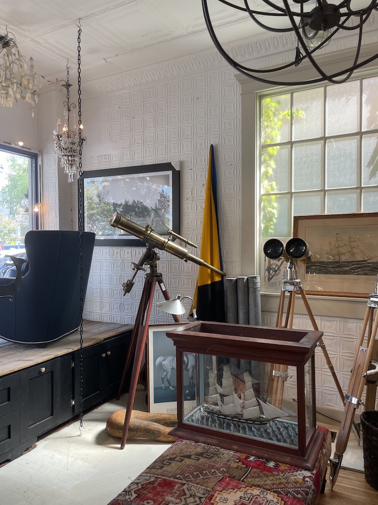 Neat and clean antique shop with chandeliers, model sail boats, telescopes, and chests. Black Swan Antiques, Sag Harbor, New York, The Hamptons.