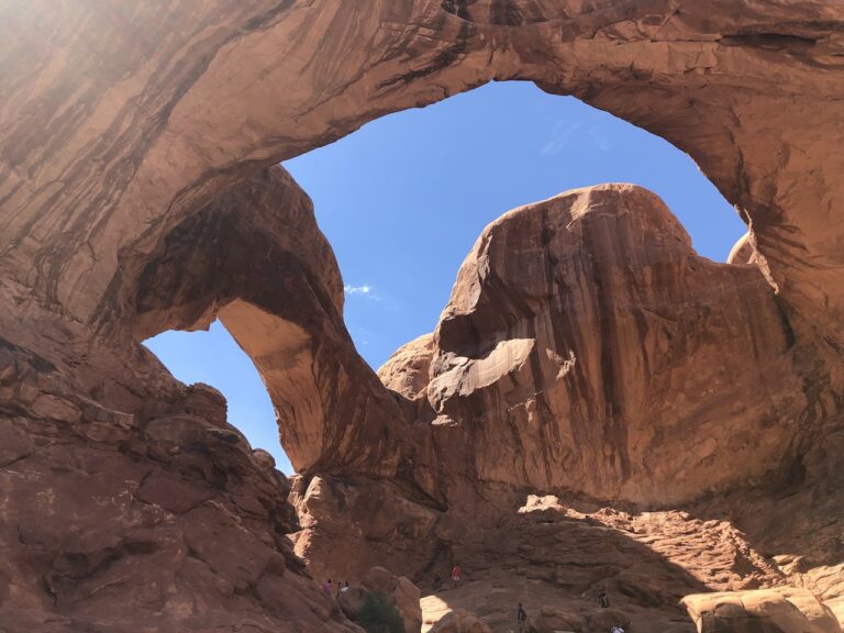 Two red rock arches conjoined and opening to bright blue sky. Double Arch, Arches National Park, Moab, Utah.