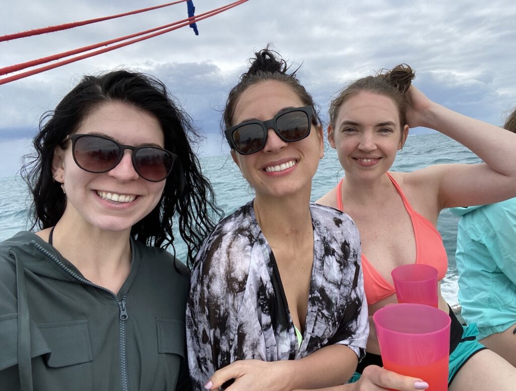 Three girls smiling and holding rum punch on snorkeling tour after snorkel excursion. Ragamuffin Tours, Caribbean Sea snorkeling, Belize Barrier Reef, Hol Chan Marine Reserve, Belize