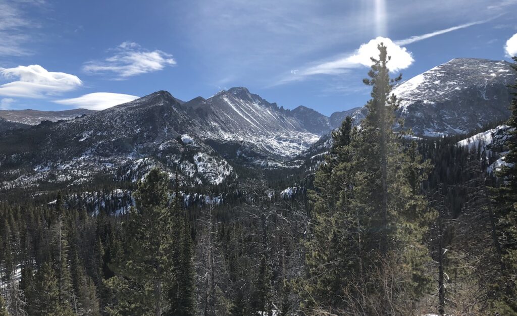 Picturesque mountain landscape, snow covered peaks with pine trees in foreground on sunny day. Winter in Rocky Mountain National Park, near Estes Park, Colorado.