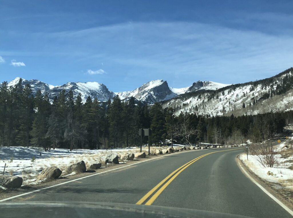 Drivers view of mountain landscape. Road winding through snow-covered mountains. Scenic drive, Rocky Mountain National Park, Estes Park, Colorado.