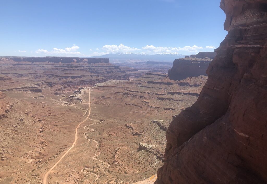 Long dirt road cutting through desert landscape into distance canyon. Shafer Canyon Overlook, Canyonlands National Park, Moab, Utah.