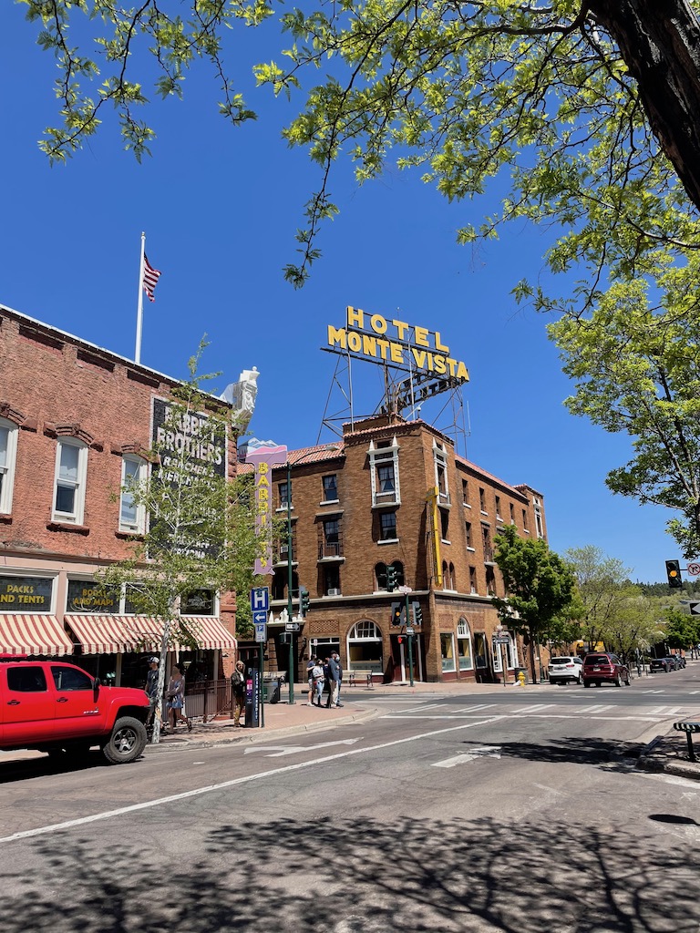 Old brick buildings with painted mural and large retro sign in yellow reading "Hotel Monte Vista". Historic Downtown Flagstaff, Arizona. What to do in Flagstaff.