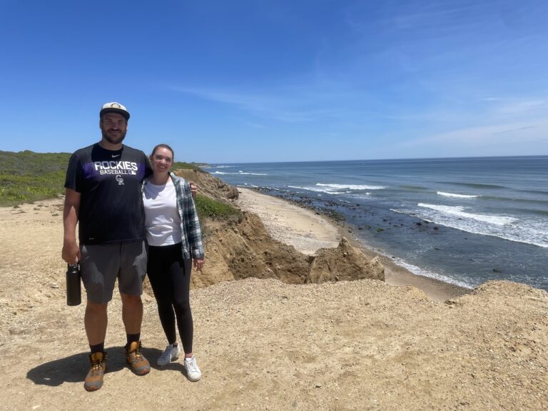 Couple standing atop beach bluffs overlooking expansive Atlantic Ocean on sunny summer day. Shadmoor State Park, Montauk, New York, The Hamptons.