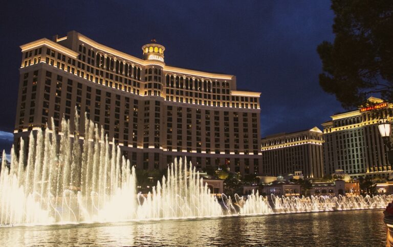 Large pool with huge fountains lit up at night, in background is huge multi-story hotel also lit up. Bellagio Fountains, Bellagio Hotel & Casino, Las Vegas, Nevada.