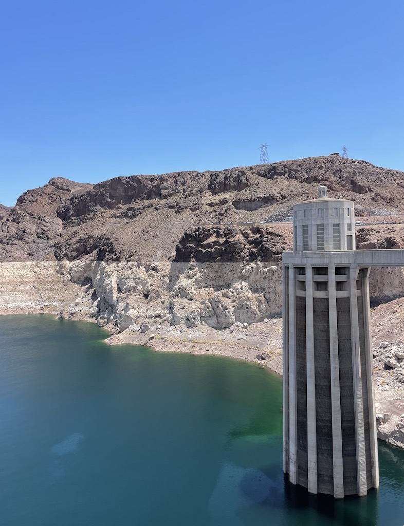 Concrete turbine in green blue water of Lake Mead in front of large red rock cliff with red rock on top and sharp line of white rock on bottom (former water line). Hoover Dam / Lake Mead, Nevada - Arizona boarder, near Las Vegas.