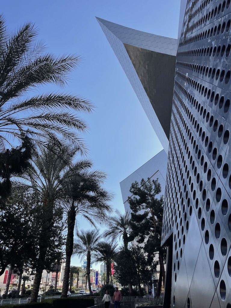 Architecturally interesting building with sharp lines and design details against bright blue sky with palm trees in background. The Shops at Crystals, the Aria Hotel, Las Vegas Strip, Nevada.