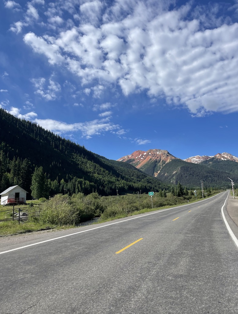 Road winding through mountain landscape on sunny summer day. Crystal Lake stop on Million Dollar Highway, Red Mountain Pass, between Silverton and Ouray, Colorado.