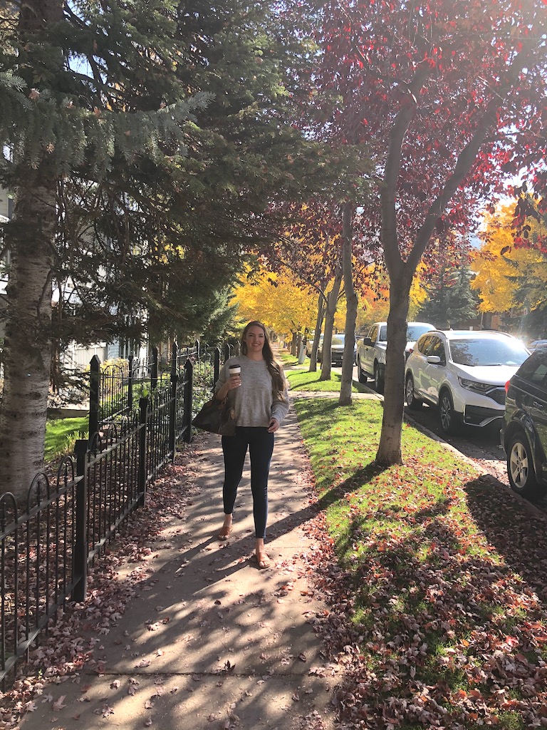 Woman walking in downtown Aspen among colorful fall trees of red, green, and yellow. Downtown Aspen, Colorado.
