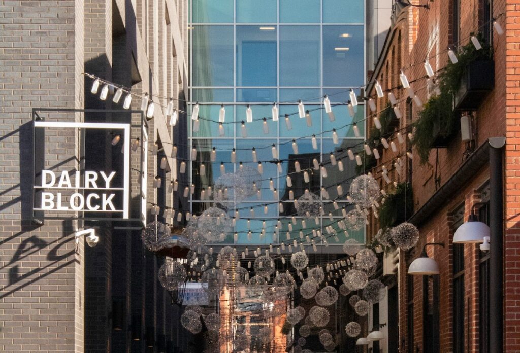 String lights over pedestrian alley with sign reading "Dairy Block" on sunny day. Denver Milk Market, Dairy Block, LoDo, Denver, Colorado.