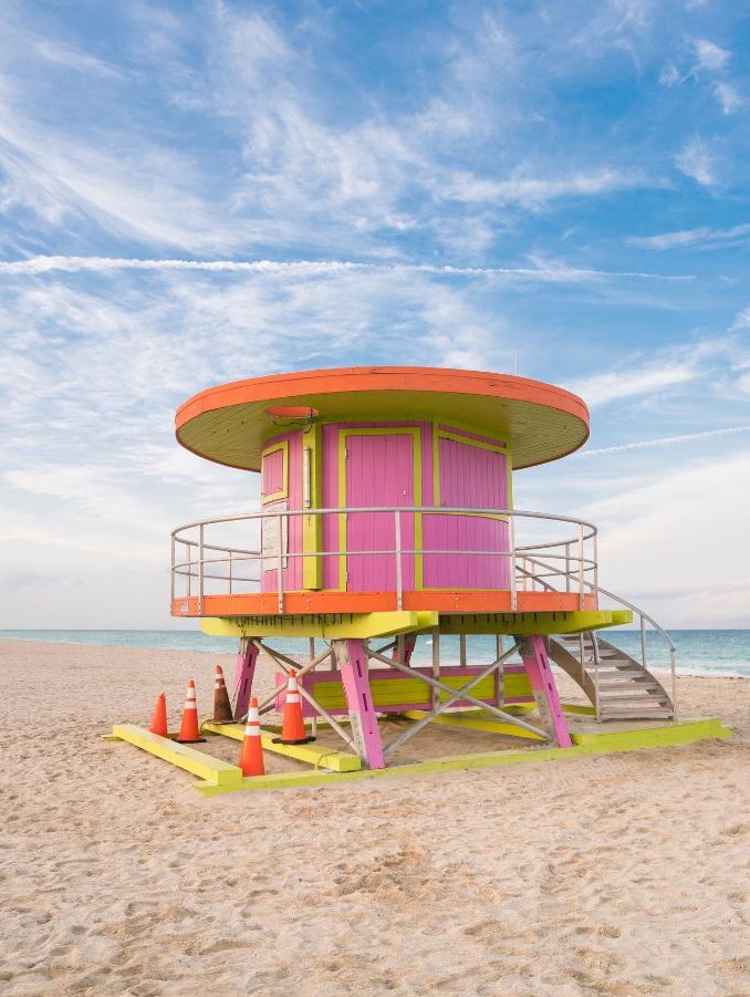 Pink, yellow, and orange circular shaped lifeguard stand on beach with ocean in background on sunny day. Miami Beach, South Beach, Miami, Florida.