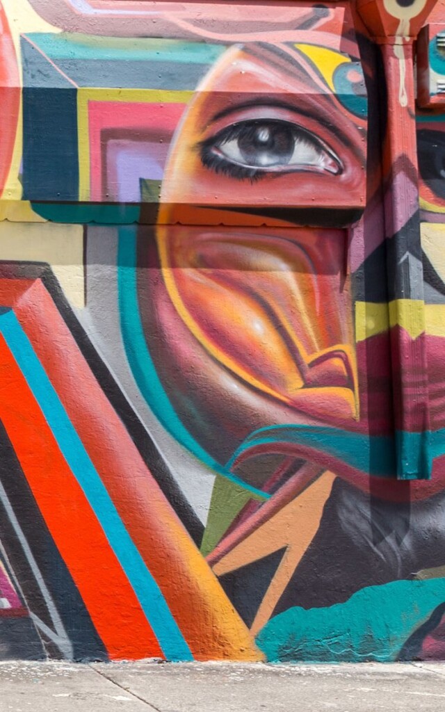 Wall covered in colorful artwork and paint, abstract shapes and realistic human eye. Street art, Wynwood Walls, Wynwood Design District, Miami, Florida.