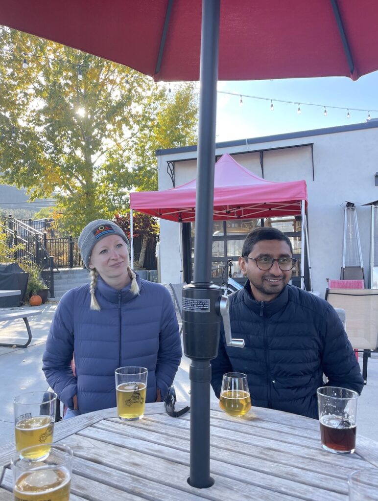 Couple sitting at outdoor table drinking craft beer on chilly afternoon in fall. Avant Garde Aleworks brewery, Estes Park, Colorado.