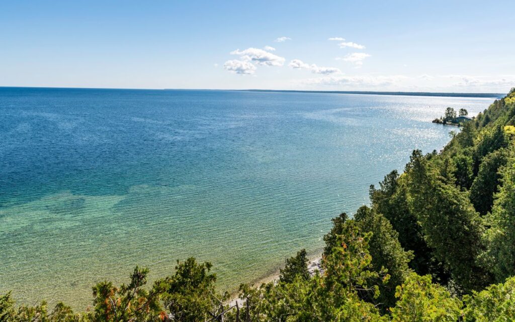 Lush green hills surrounding bright blue cove of Lake Huron on sunny summer day. Mackinac Island, Michigan.