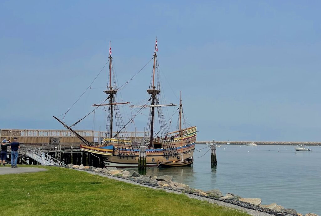 Large, two-masted wooden boat docked on calm water. Mayflower II replica, Pilgrim Memorial State Park, Plymouth, Massachusetts.
