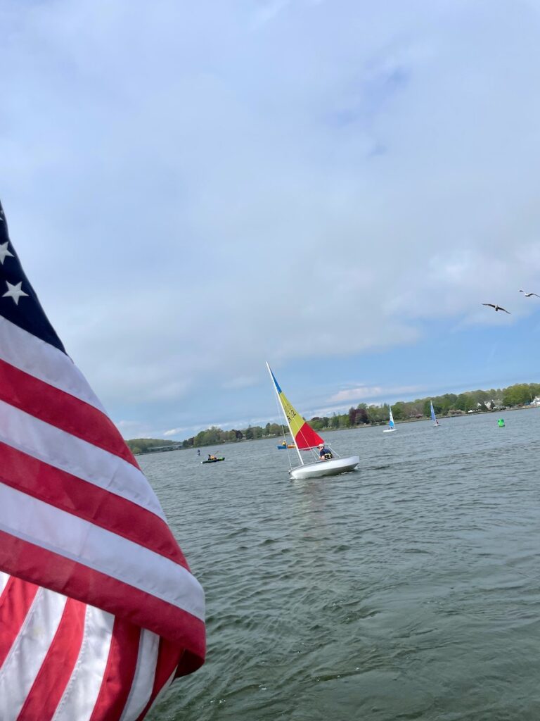 View from boat of young kids learning to sail on calm tidal river on sunny summer day. Boat tour, sailing lessons, Mystic, Connecticut.