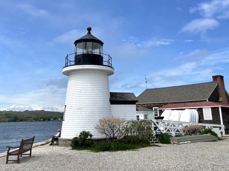 Small replica lighthouse overlooking the calm Mystic River on sunny day. Maritime Seaport Museum, Mystic, Connecticut.