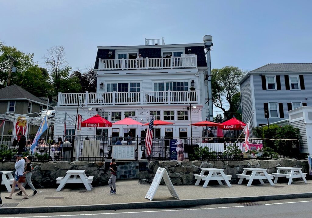 Shops and restaurants bustling with people, lining Water Street on sunny day. Water Street, Plymouth, Massachusetts.