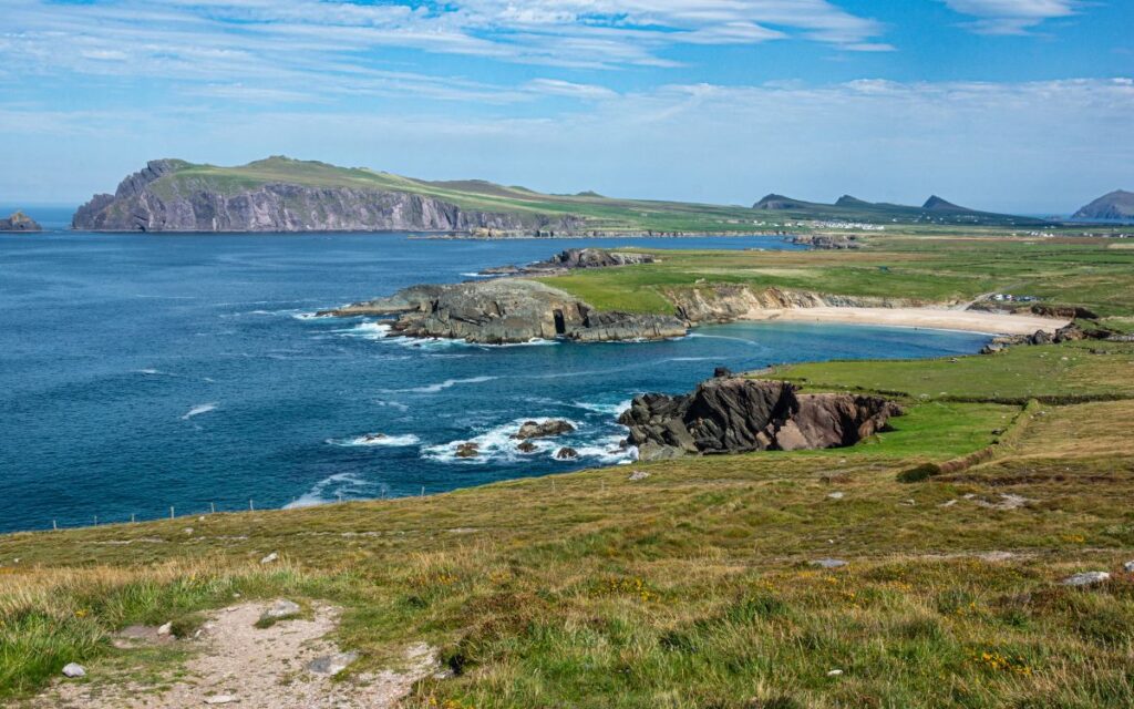 Green coastline of Atlantic Ocean with mix of rocky cliffs and white sand beach on sunny summer day. Clogher Head, Dingle Peninsula, Dingle, Ireland.