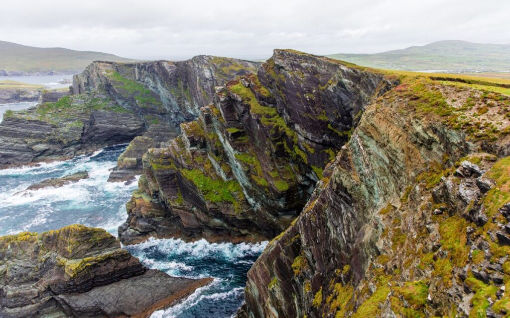Jagged rocky cliffs against Atlantic Ocean on gloomy day. Scenic drive, Ring of Kerry, County Kerry, Ireland.