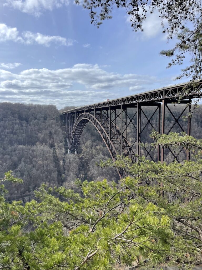 Steel, single arch bridge spanning huge gorge covered in trees on sunny late-fall day. River Gorge Bridge Overlook, New River Gorge National Park, West Virginia.