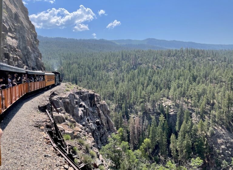 Train winding through mountains and pine forest with panoramic views on sunny summer day. Durango & Silverton Narrow Gorge Railway Train, San Juan Mountains of the Rocky Mountains, Durango, Colorado.