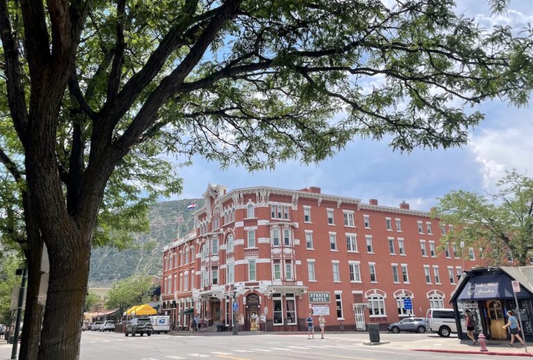 Old red brick building in downtown historic Durango with mountain views in background during summer. Historic Strater Hotel, Downtown Durango, Colorado.