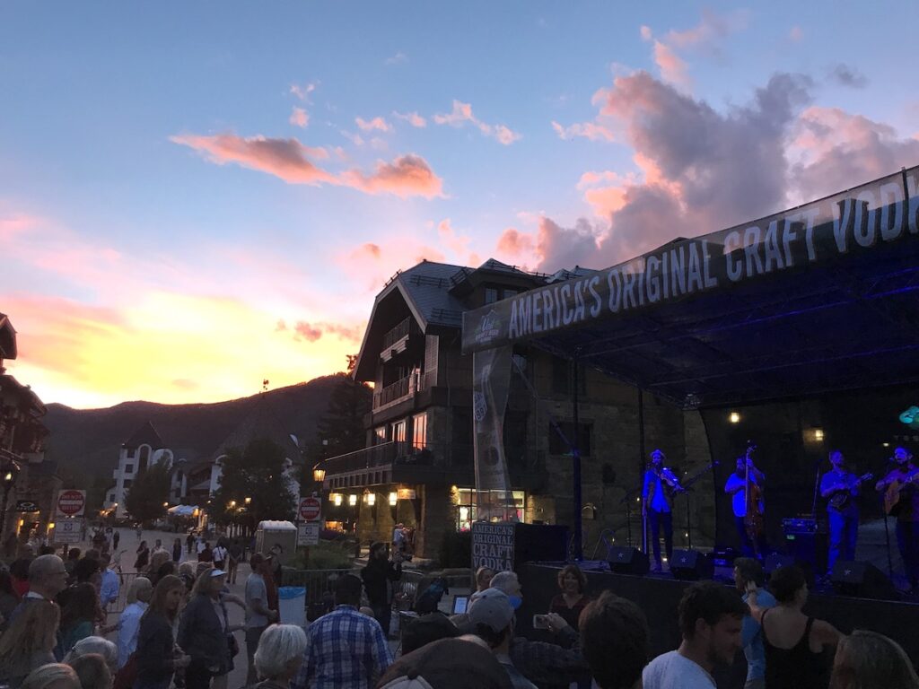 Crowd watching live music on concert stage with colorful sunset in background. Gerald R. Ford Amphitheater, Vail Craft Beer Classic, Vail Village, Vail, Colorado.