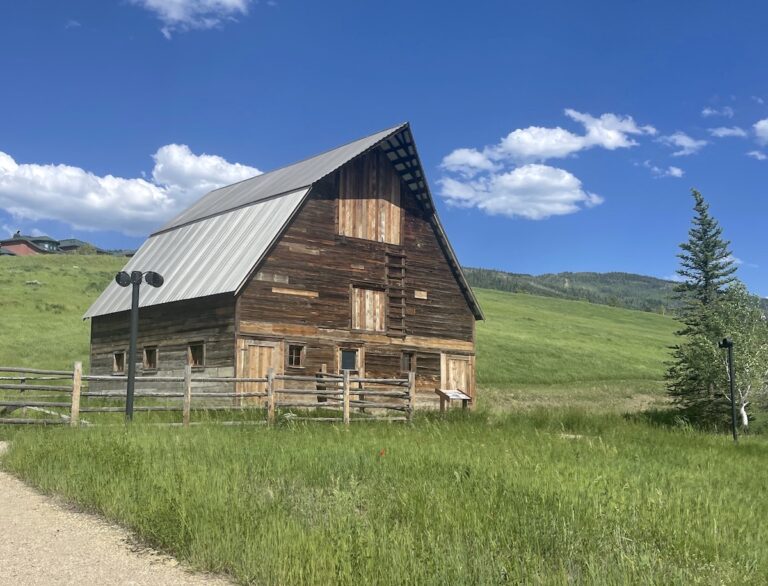 Historic wooden barn on grassy field in mountains on sunny summer day. Arnold Barn, Steamboat Springs, Colorado.