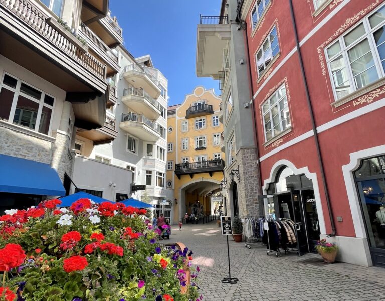Colorful buildings surrounding cobblestone courtyard full of colorful flowers on sunny summer day. The Arrabelle Hotel, Lionshead Village, Vail, Colorado.