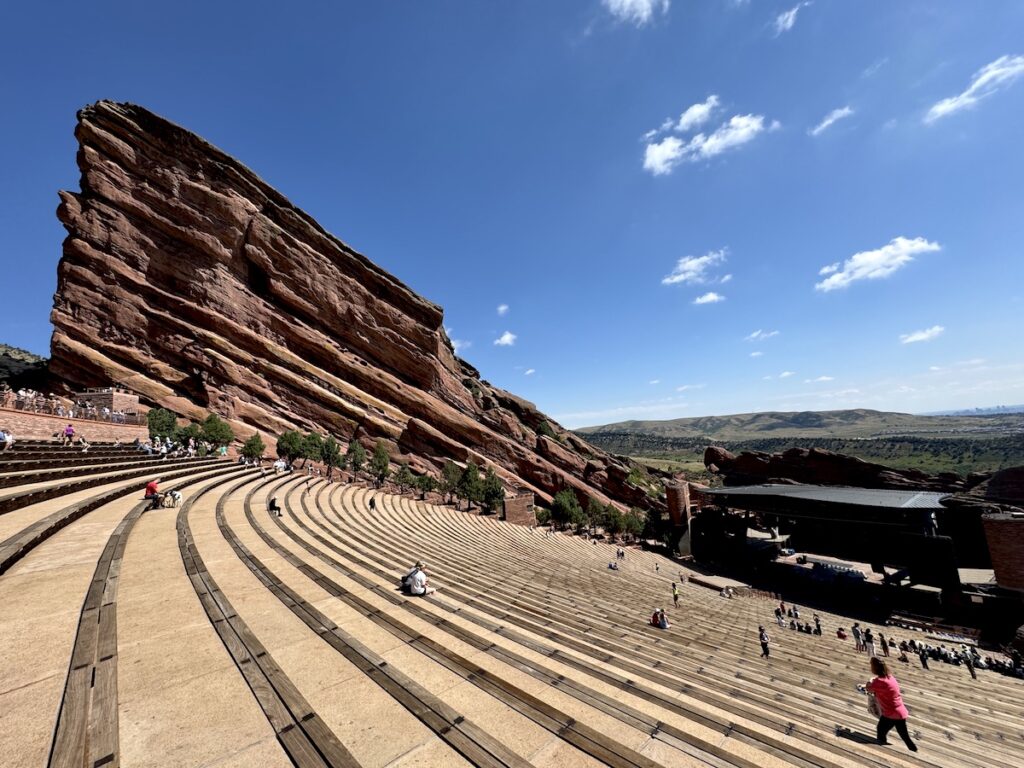 Large outdoor amphitheater surrounded by huge red rocks on bring sunny morning. Red Rocks Park & Amphitheatre, Morrison, Colorado, near Denver.