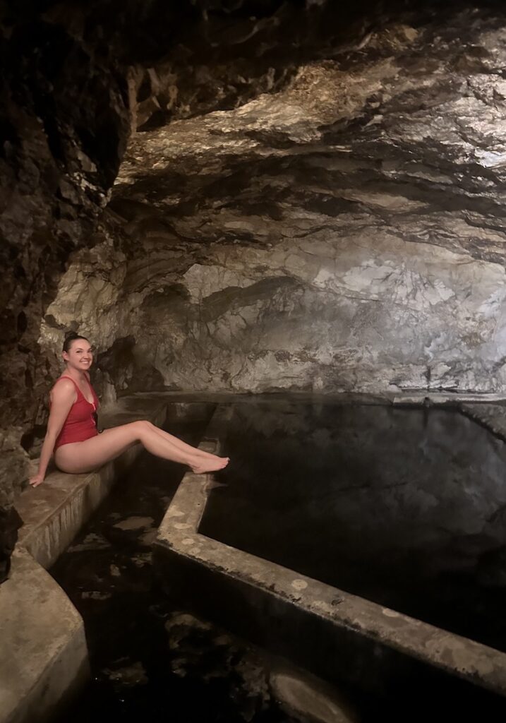 Woman sitting next to hot springs in rocky vapor cave. Wiesbaden Hot Springs Spa & Lodge, Ouray, Colorado.