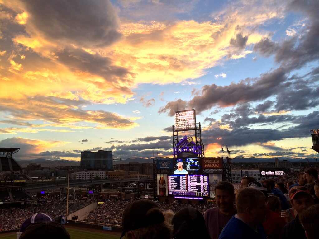 Colorful sunset over large jumbotron and full stadium at baseball game in summer. MLB Colorado Rockies, Coors Field, Denver, Colorado.