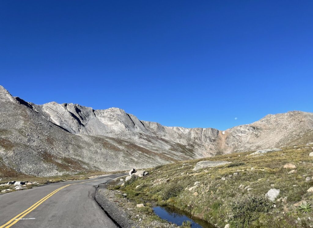 High elevation mountain road in treeless alpine tundra heading towards rocky peaks on cloudless summer day. Mount Blue Sky Scenic Byway, Mount Blue Sky Recreation Area, 14ers, Colorado.