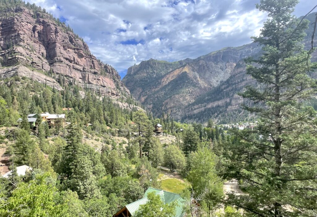 View from above of small mountain town surrounded by rocky mountains on sunny summer day. Hiking the Perimeter Trail, Ouray, Colorado.