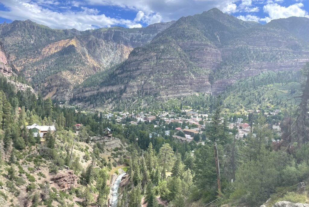 View from above of small mountain town surrounded by rocky mountains on sunny summer day. Hiking the Perimeter Trail, Ouray, Colorado.