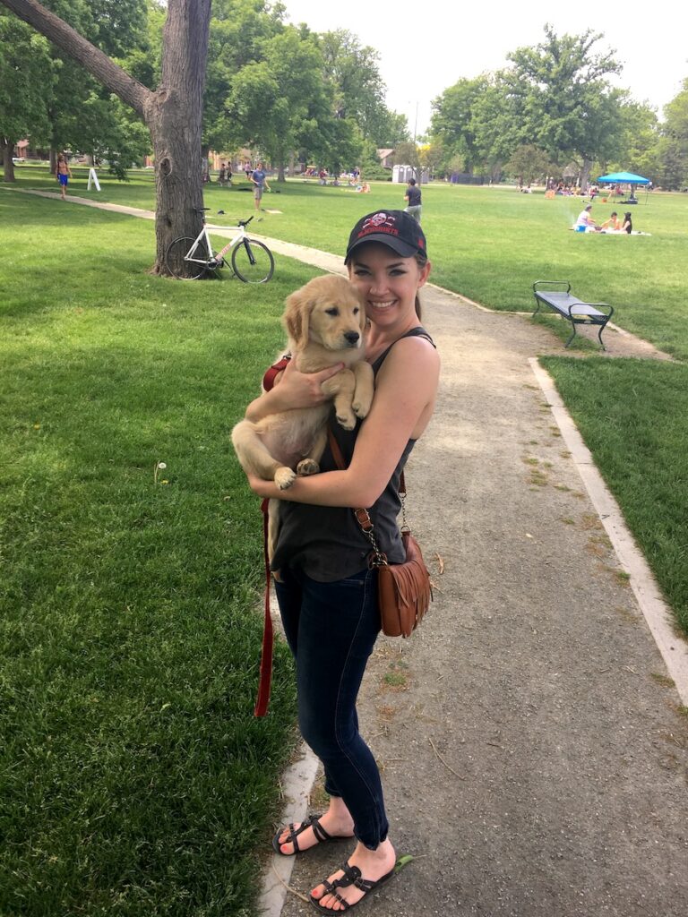 Woman holding Golden Retriever puppy in park during summer. Washington Park, Wash Park, Denver, Colorado.