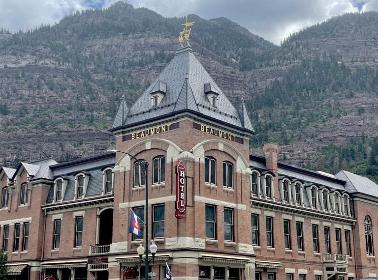 Historic red brick building with mountain background and front sign reading "Beaumont Hotel." Beaumont Hotel, Ouray, Colorado.