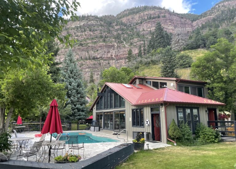 Boutique hotel with large windows overlooking hot spring pool and mountain backdrop. Wiesbaden Hot Springs Spa & Lodgings, Ouray, Colorado.