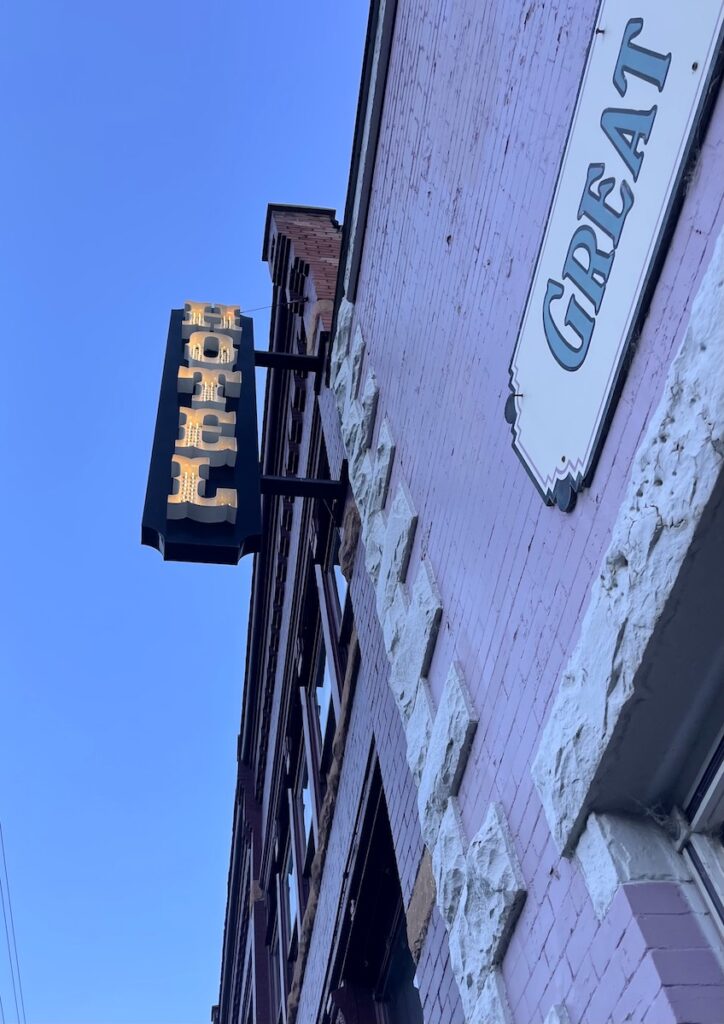 Historic building painted purple with large neon sign lit up reading "HOTEL" on summer evening. Teller House Hotel, Silverton, Colorado.
