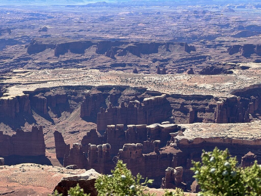Red rock canyon with tall spires between large flat mesas on sunny afternoon. Grand View Overlook, Canyonlands National Park, Island In The Sky, Moab, Utah.
