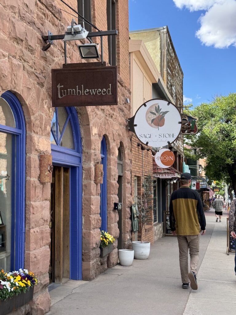 Person walking along street lined with historic Southwest sandstone buildings on sunny summer day. Shopping in downtown Moab, Utah.