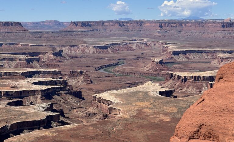 Sweeping canyon views of red canyon with river flowing through it on sunny day. Green River Overlook, Canyonlands National Park, Island In The Sky, Moab, Utah.