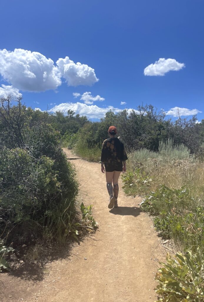 Woman hiking through desert-like landscape on sunny day in summer. Hiking to Painted Rock Overlook, Black Canyon of the Gunnison National Park South Rim, near Montrose, Colorado.