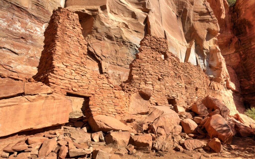 Ruins of Sinagua Indigenous people, red stone structure against smooth red sandstone cliff. Palatki Heritage Site, Sedona, Arizona.